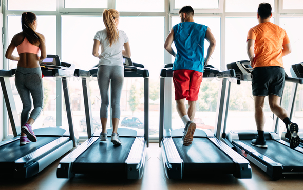 Picture of sporty people running on treadmill in gym